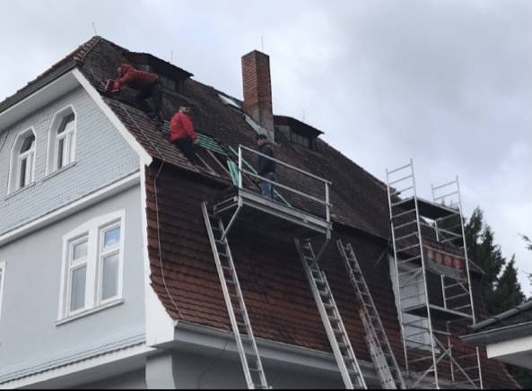 Ein Mann arbeitet am Dach eines Hauses.