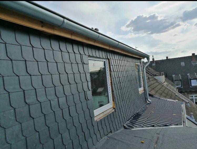 Auf dem Dach eines Gebäudes liegen graue Ziegel.